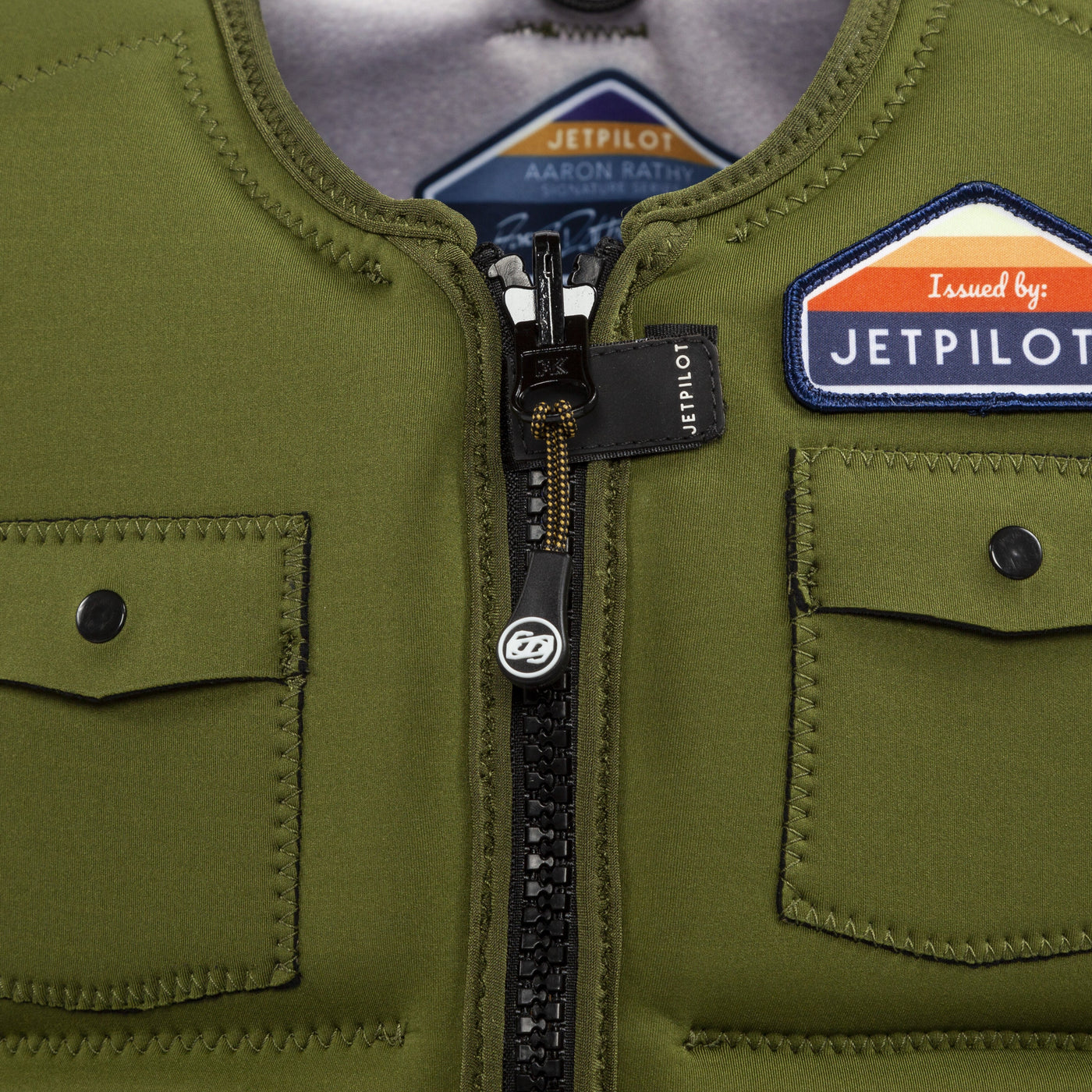 Closeup view showing zipper and patch of the Aaron Rathy of the Jetpilot's Aaron Rathy Signature Comp Vest Moss colorway.